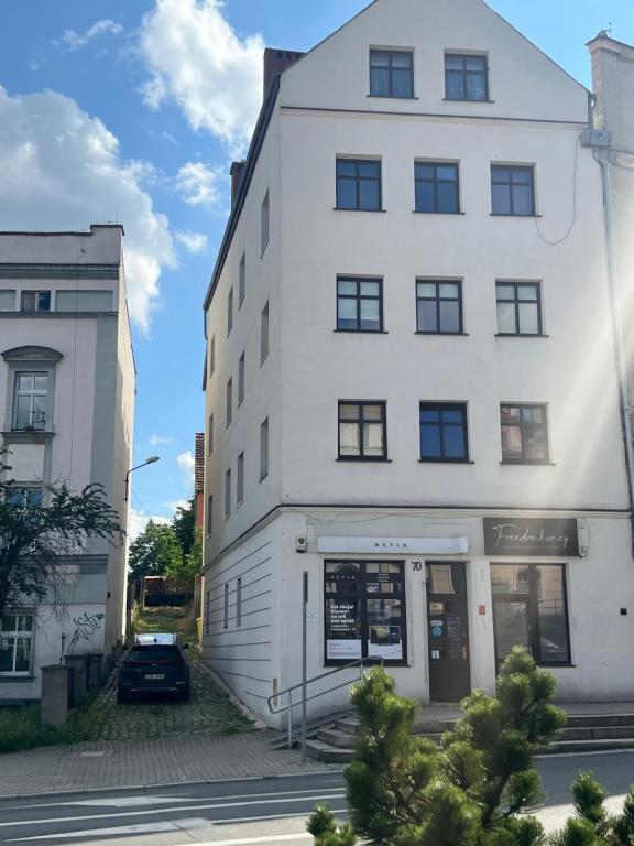 un edificio blanco con un coche aparcado delante de él en Apartament Centrum, en Świdnica