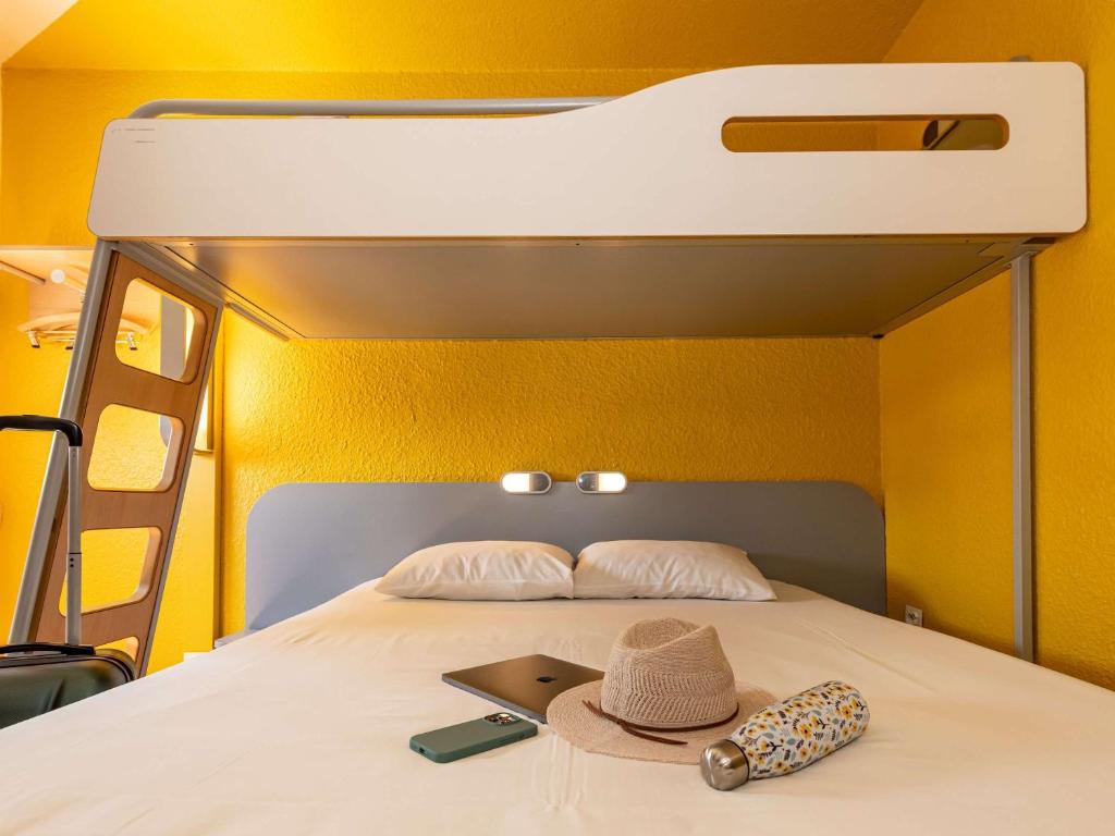 - un lit avec un chapeau et un ordinateur portable dans l'établissement ibis budget Strasbourg Sud Illkirch, à Geispolsheim