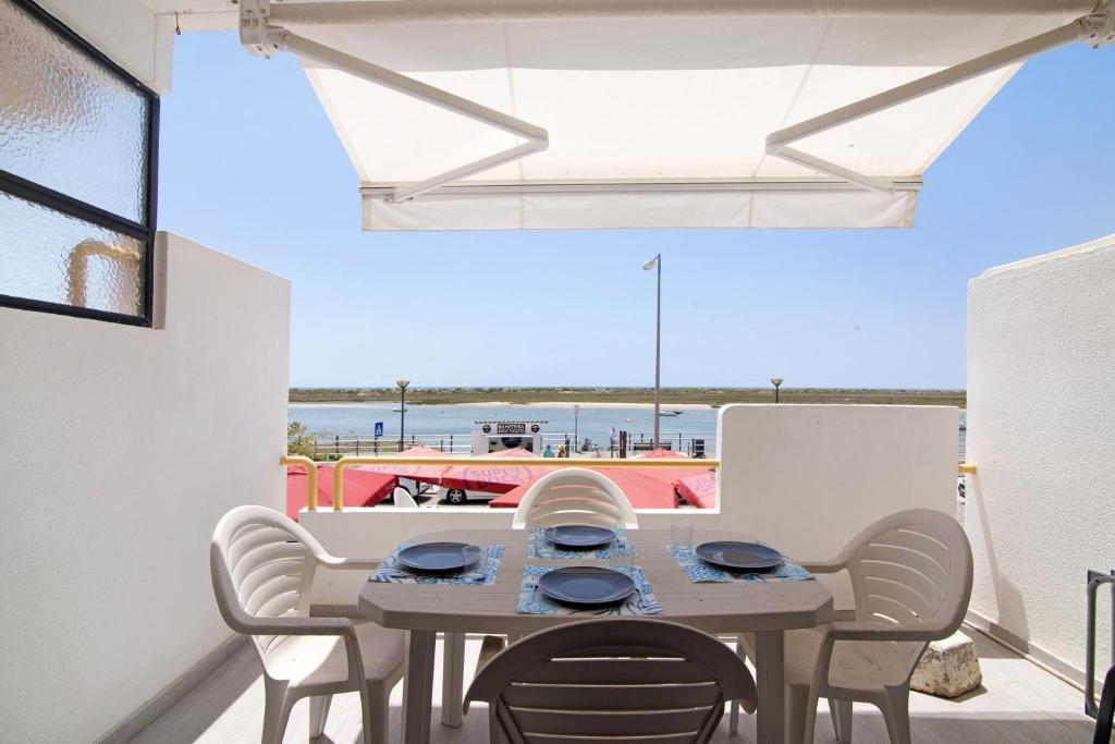 una mesa y sillas en un balcón con vistas al océano en Cabanas Mar 96 en Cabanas de Tavira