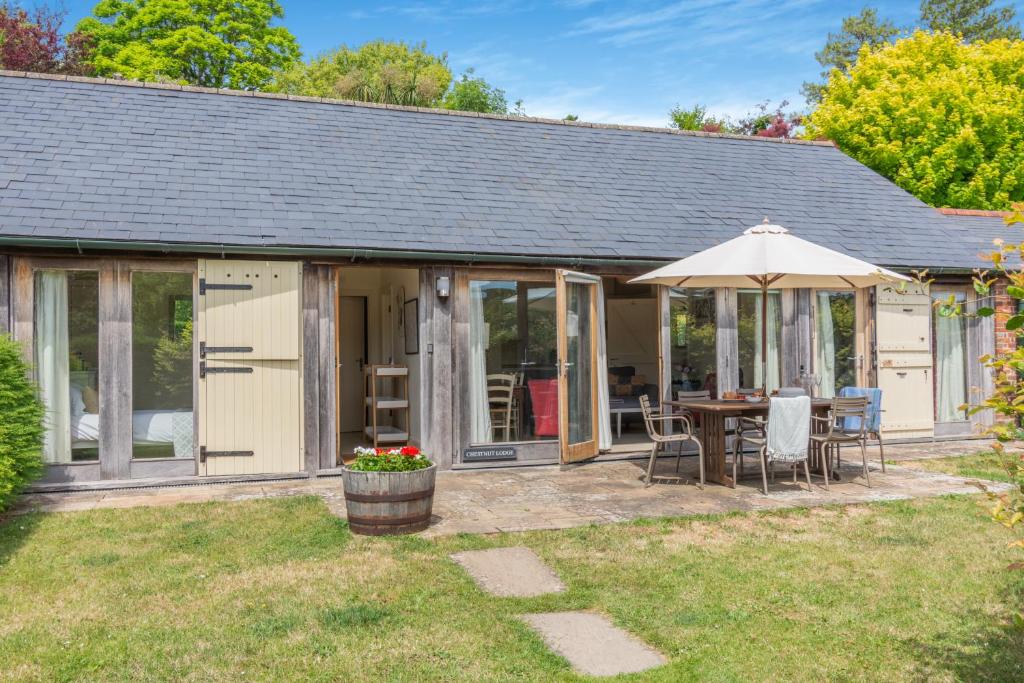 a cottage with a table and an umbrella at Chestnut Lodge in East Dean