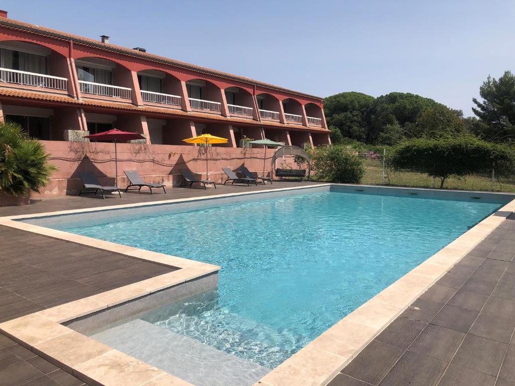 a swimming pool in front of a building at The Originals City, Le Mas de Grille, Montpellier Sud in Saint-Jean-de-Védas