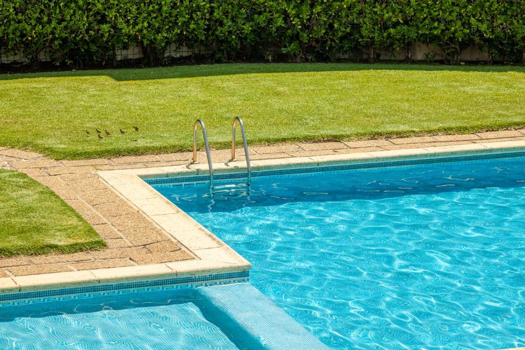 a blue swimming pool with a grassy field next to it at Apartamento Bela Vista - Minho's Guest in Esposende