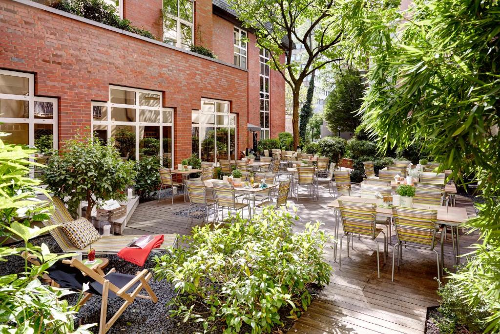 a patio with tables and chairs in front of a brick building at Lindner Hotel Cologne City Plaza, part of JdV by Hyatt in Cologne
