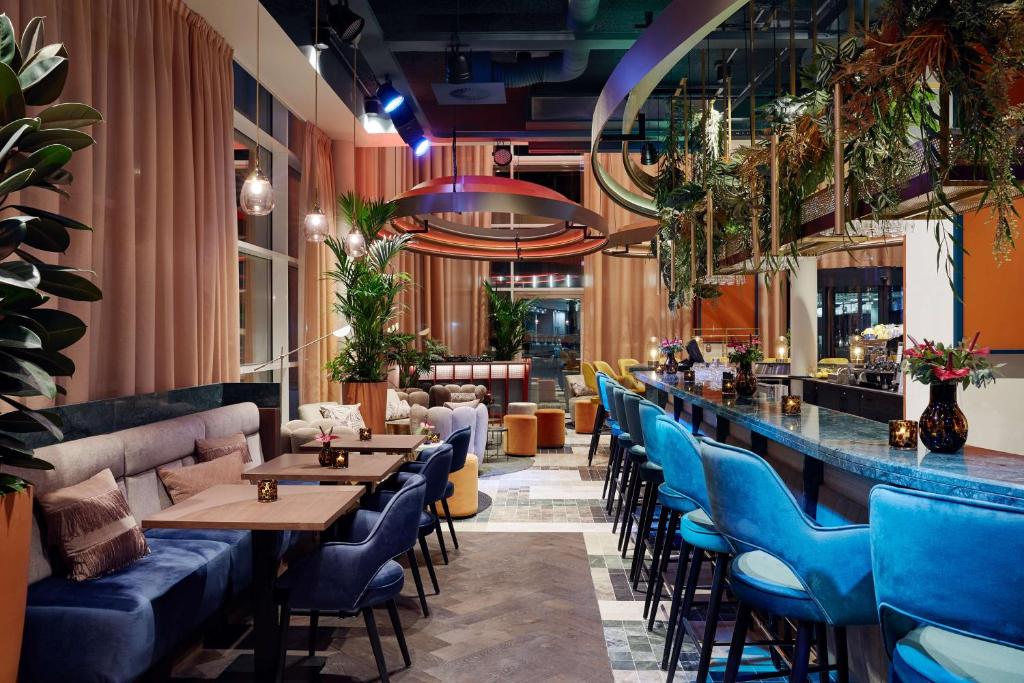 un restaurant avec des chaises bleues et un bar dans l'établissement Lindner Hotel Antwerp, part of JdV by Hyatt, à Anvers