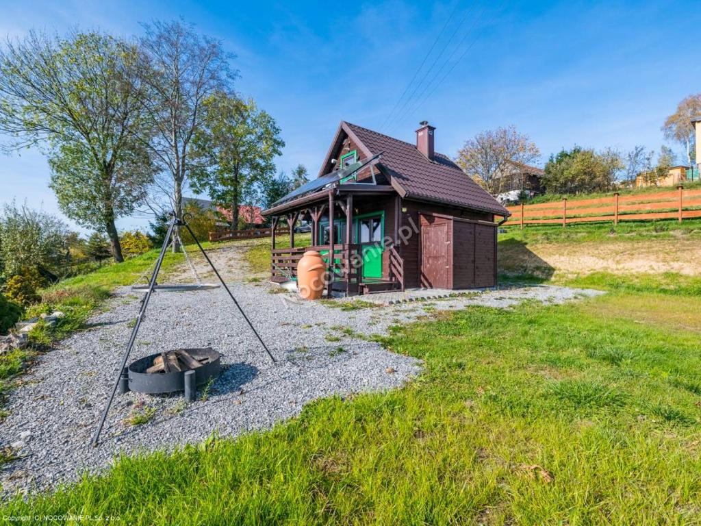 ein kleines Haus mit einem Spielplatz davor in der Unterkunft Domek Pod Groniem in Jasnowice