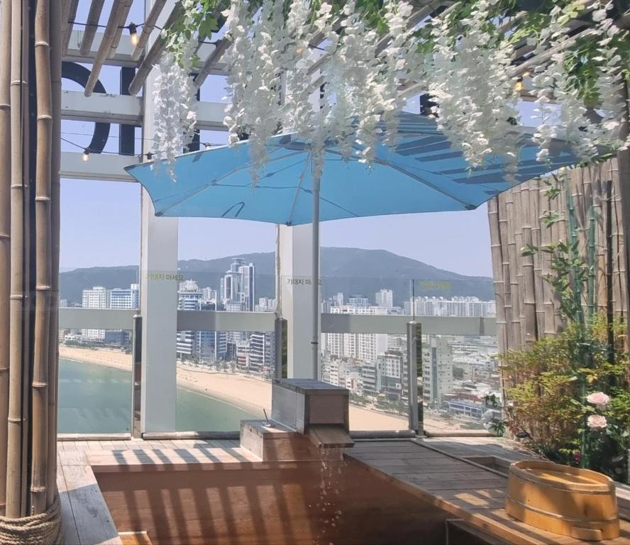 een blauwe parasol in een gebouw met uitzicht op een strand bij Gwanganli The Club Hotel in Busan