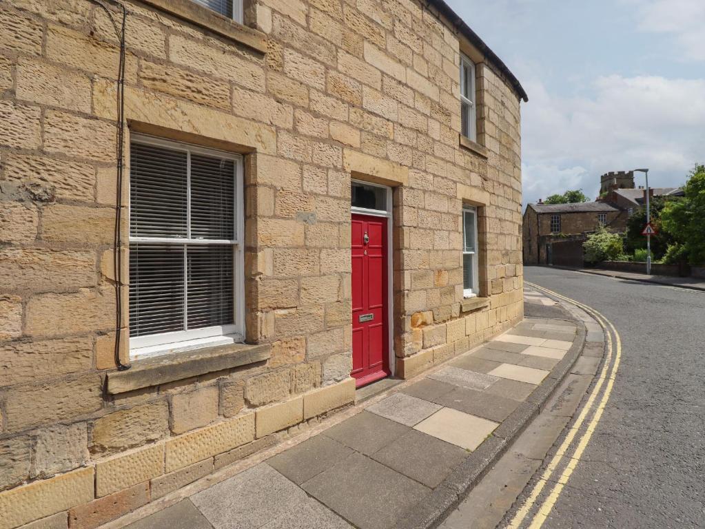 un bâtiment en briques avec une porte rouge dans une rue dans l'établissement White Feathers, à Alnwick