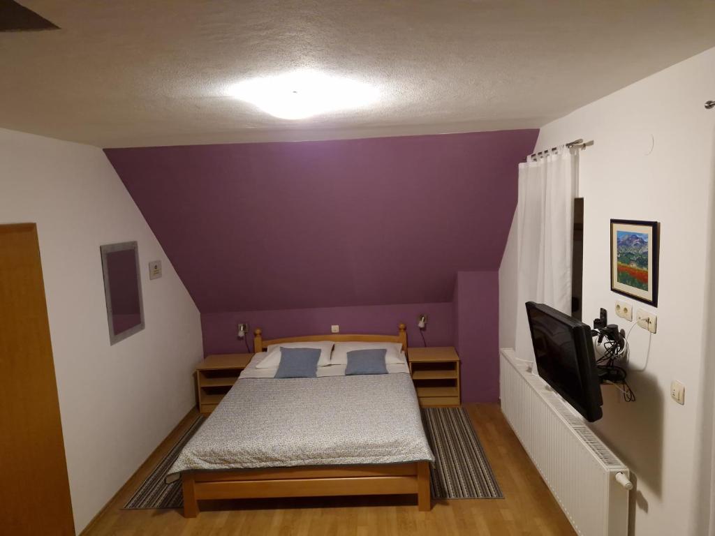 a bedroom with a bed and a purple wall at Guest house Wolf II in Plitvička Jezera