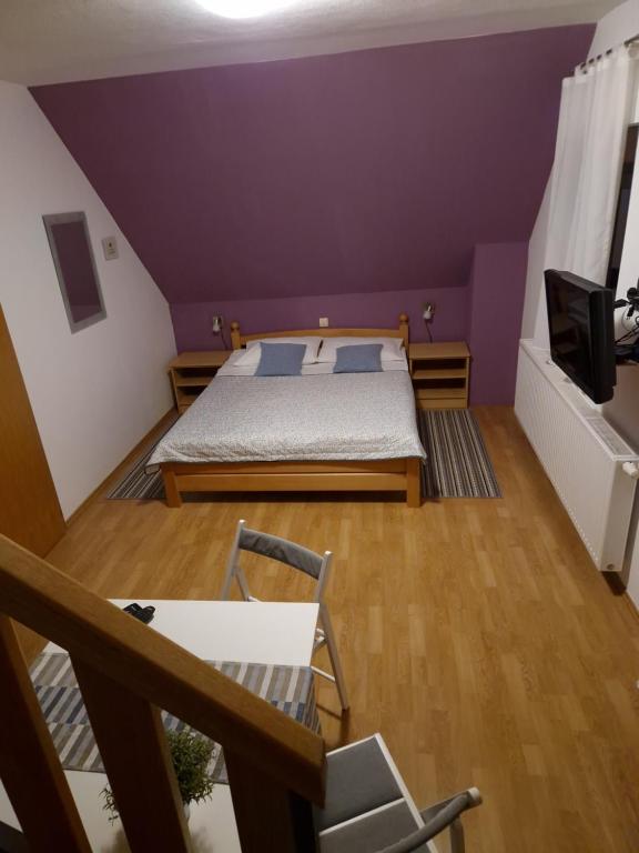 a purple room with a bed and a tv at Guest house Wolf II in Plitvička Jezera