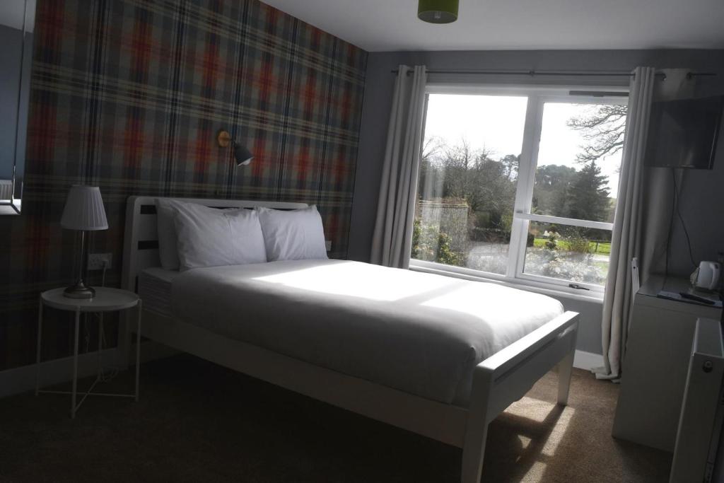 a bedroom with a white bed and a window at Lunan House in Arbroath