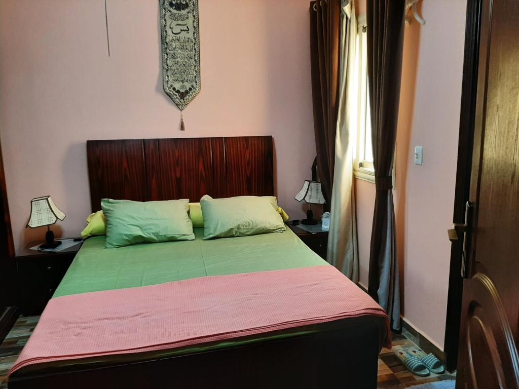 a bedroom with a bed with a green comforter at ستيلا هايتس الساحل الشمالي in Sīdī ‘Abd ar Raḩmān