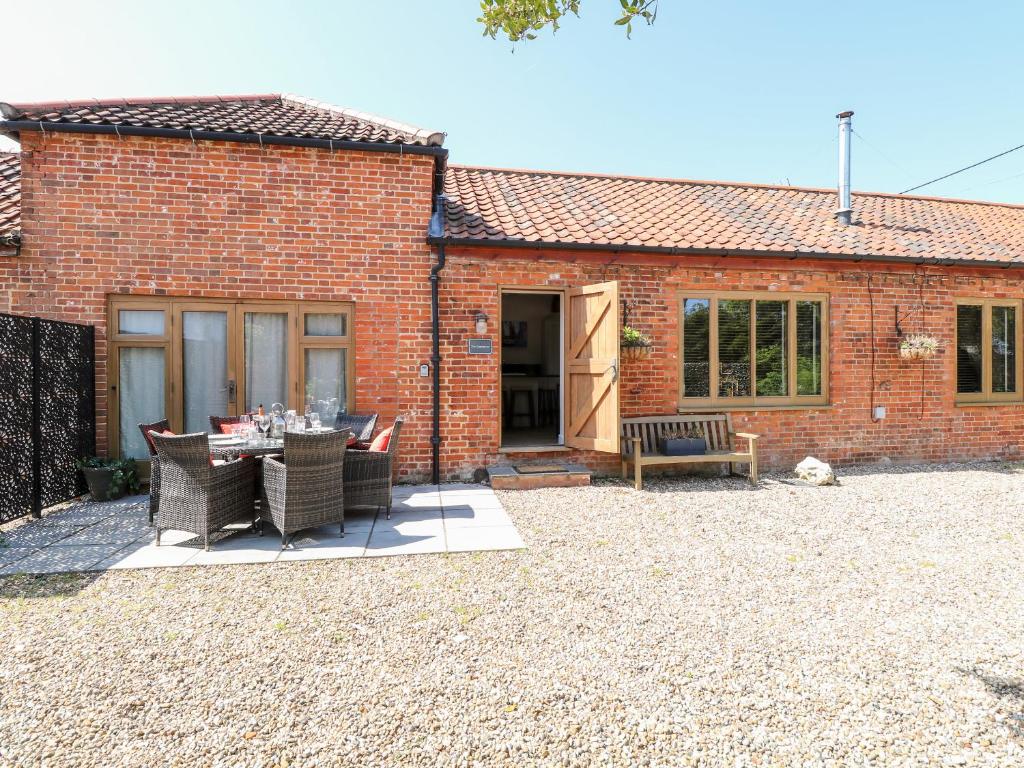 a brick house with a patio with a table and chairs at The Barnhouse in North Walsham