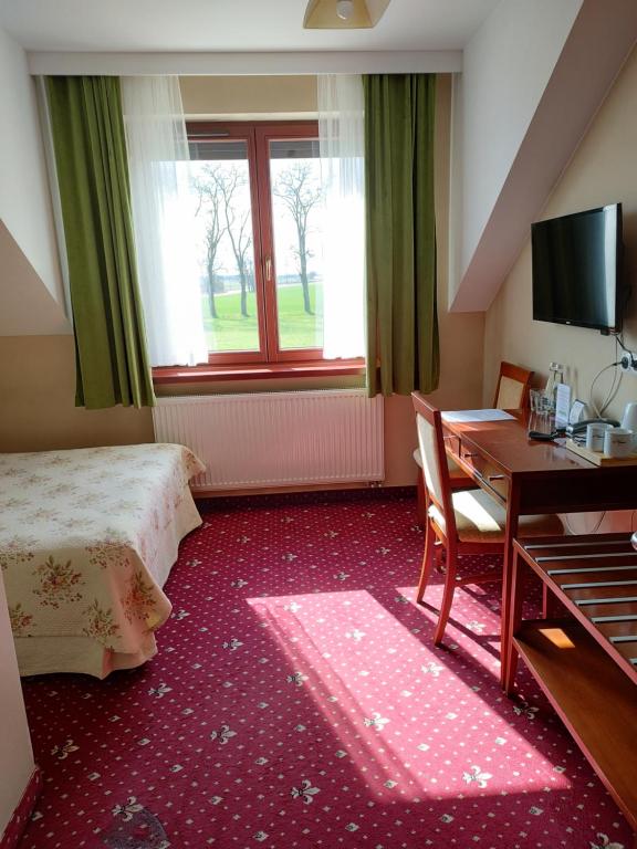 a hotel room with a bed and a desk and a window at Gospoda Pazibroda in Maków Mazowiecki