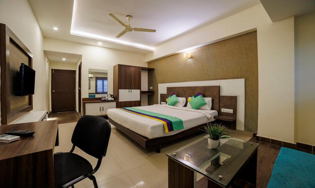 Habitación de hotel con cama y escritorio en Treebo Trend Pride, en Mysore