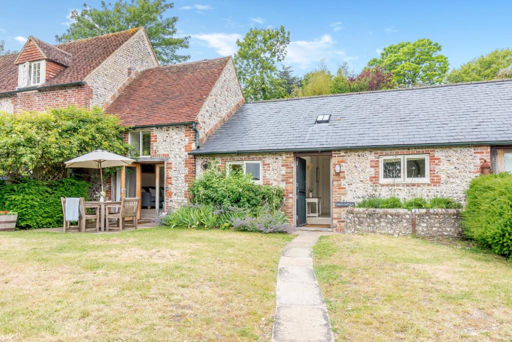 a stone house with a patio and a yard at Giddy Cottage in Eastdean