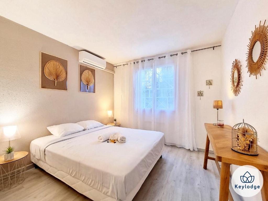 a bedroom with a large white bed and a desk at Cazapi 3 étoiles - T2 de 47 m2 à Saint-Denis in Saint-Denis