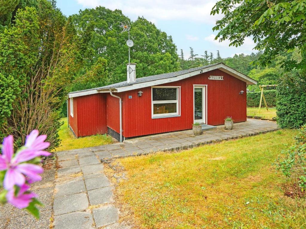 a red shed with a patio in a yard at 6 person holiday home in Alling bro in Nørager