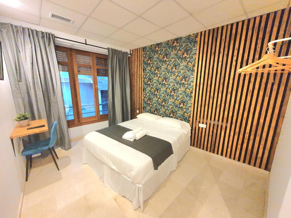 1 dormitorio con cama, escritorio y ventana en PLAZA HOME en Valencia