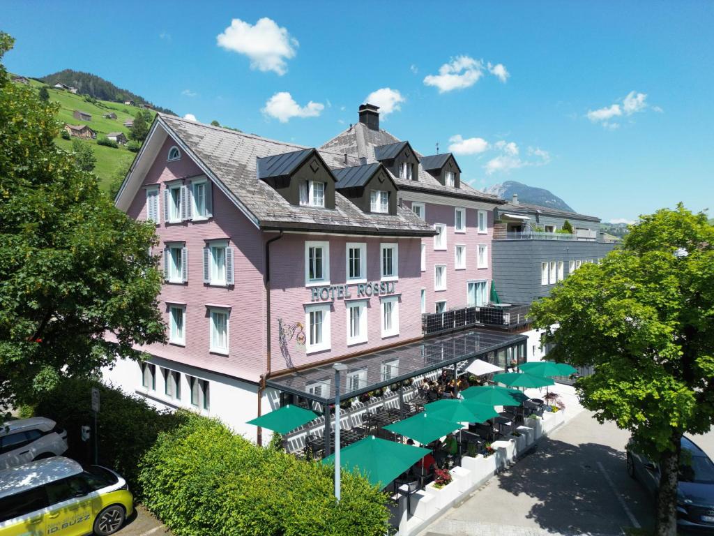 un edificio rosa con sombrillas verdes delante en Hotel Restaurant Rössli en Alt Sankt Johann