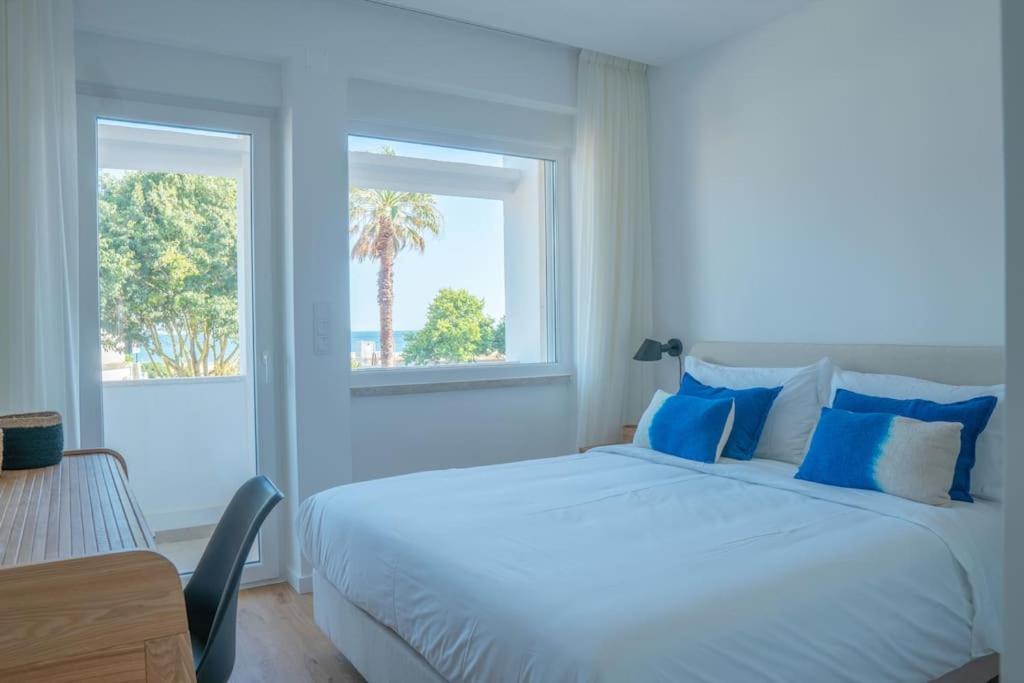 1 dormitorio con 1 cama blanca grande con almohadas azules en NEW Estrela da Praceta Apt w/ 3 Suites & Oceanview en Carcavelos