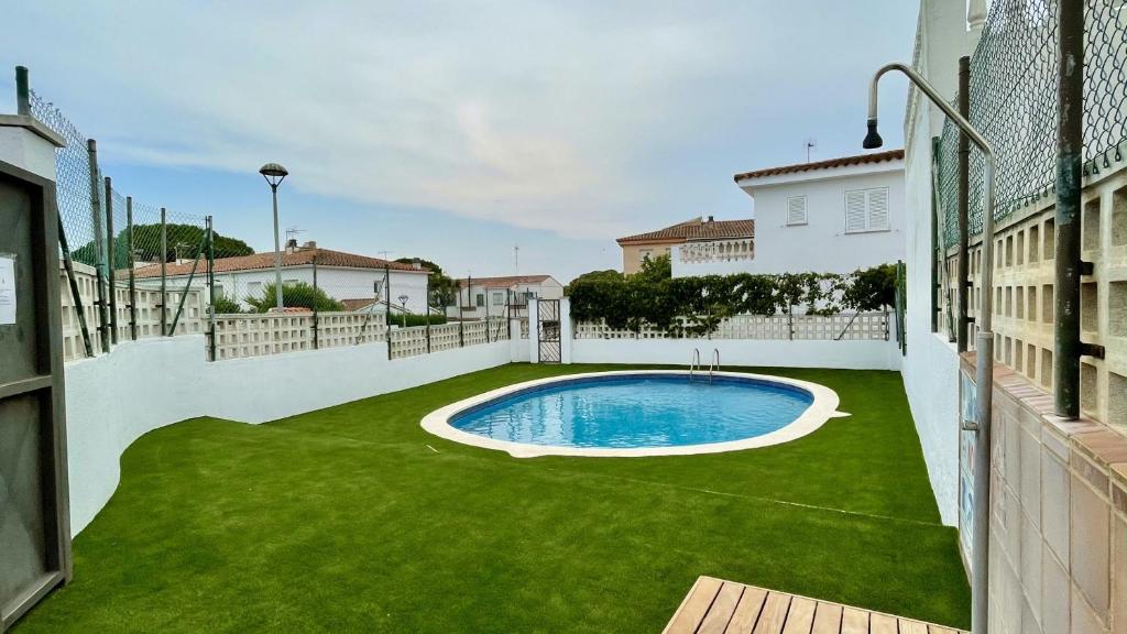 un patio trasero con piscina y césped verde en Casas La Vinya I, en L'Escala