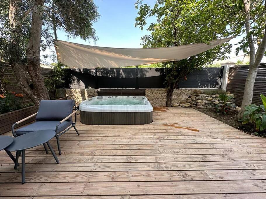 a patio with a hot tub and a chair and a tent at Maison à deux pas des plages avec jardin, terrasses et spa. in Mèze