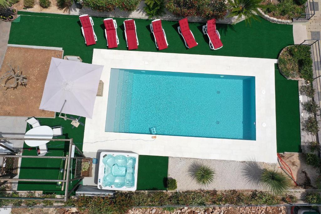 een uitzicht over een zwembad met rode stoelen bij Waterfront Apartments with Pool in Novalja