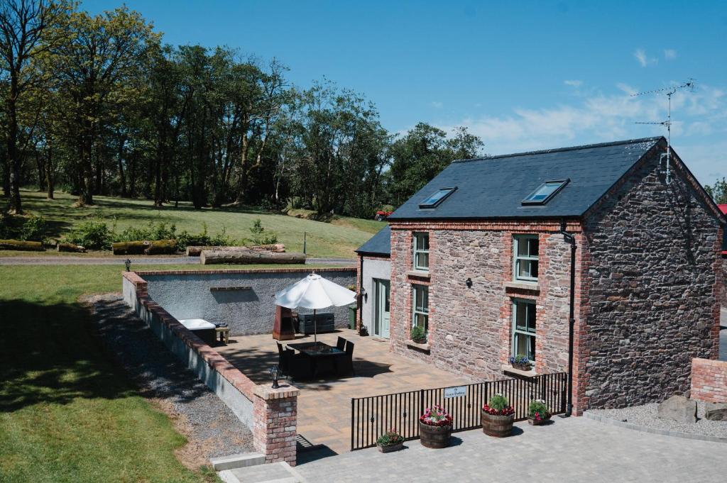 een bakstenen huis met een zwembad en een patio bij Tranquil Rustic Cottage in Dromore