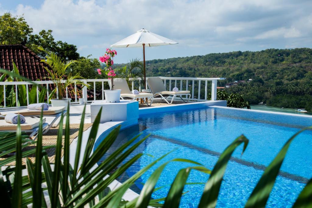 - une piscine avec des chaises et un parasol au-dessus d'une maison dans l'établissement Stardust Villas, à Nusa Lembongan