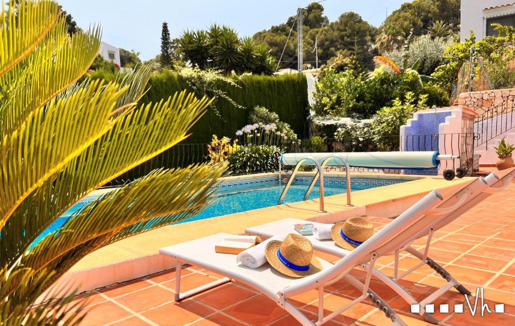 Una mesa con sombreros al lado de una piscina. en VH CostaBlanca - ZEN, en Fanadix
