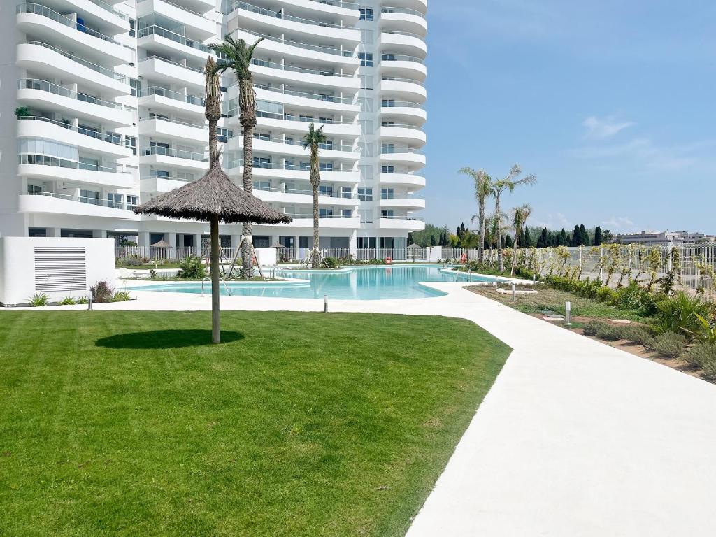 un gran edificio de apartamentos con piscina y césped en Global Properties, Apartamento para 5 personas con terraza y vistas a la piscina, en Canet de Berenguer
