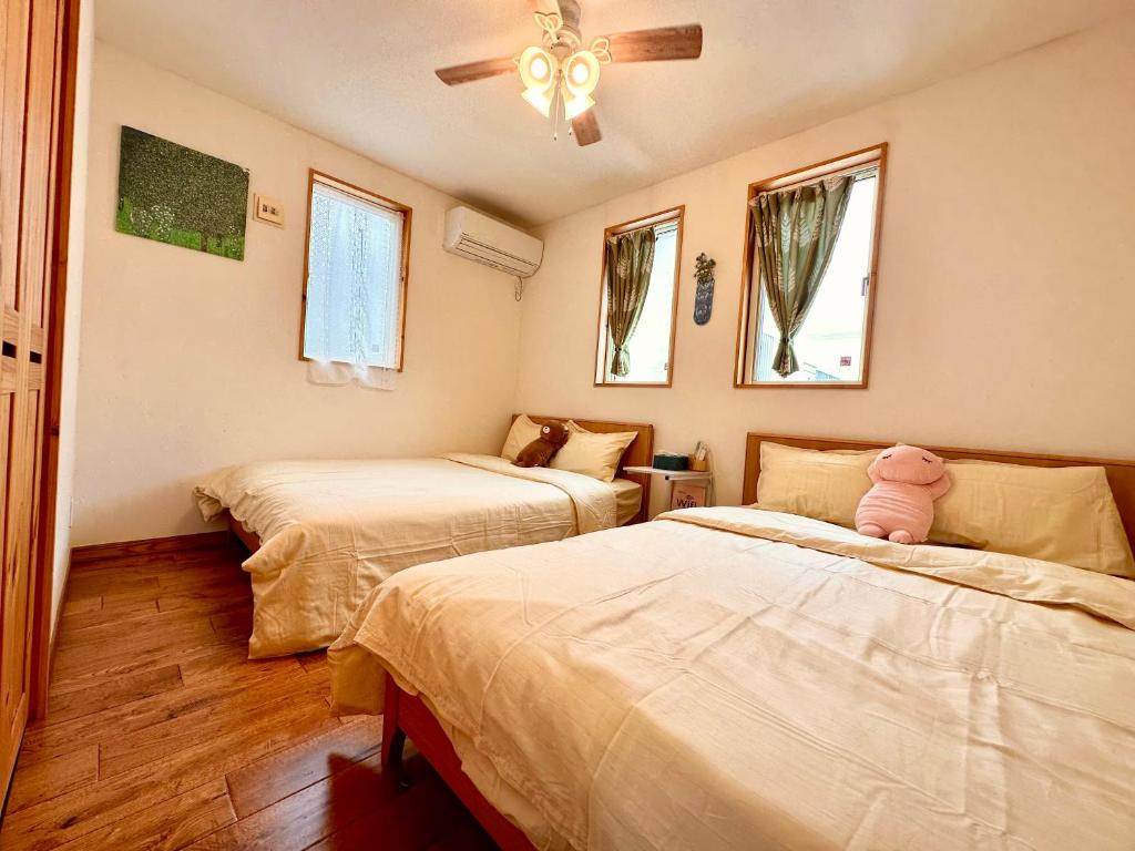 ein Schlafzimmer mit 2 Betten und einem rosa ausgestopften Tier auf dem Bett in der Unterkunft Villa Yui in Ishigaki-jima