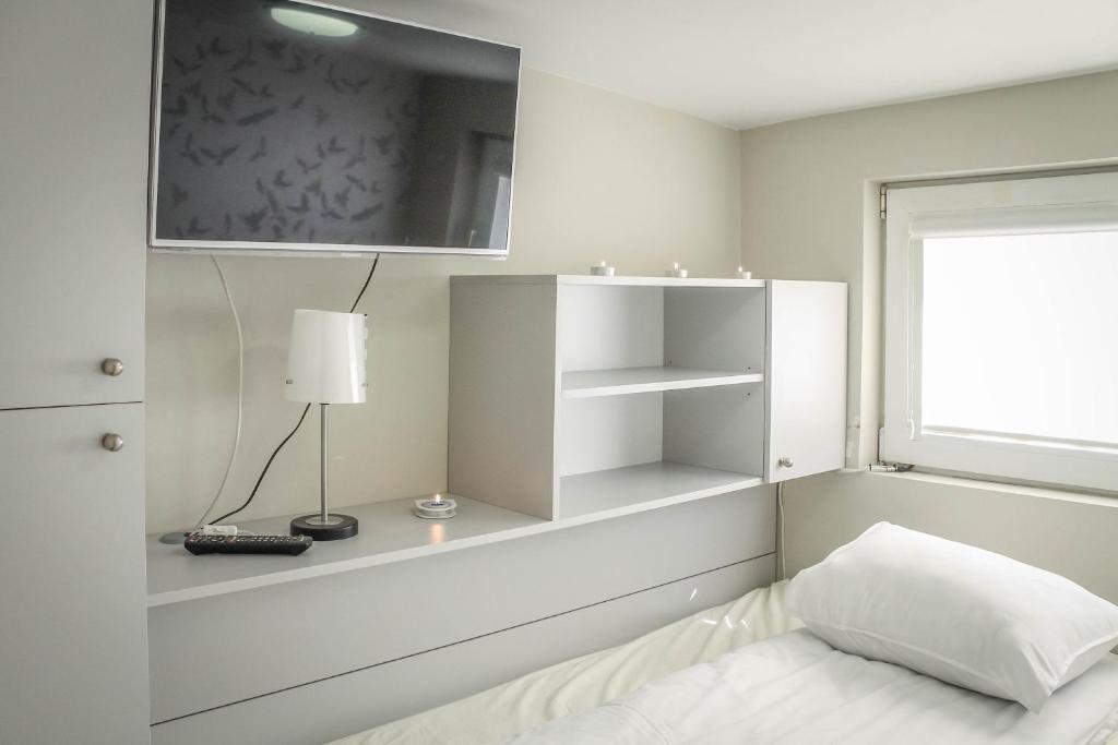 a white bedroom with a bed and a window at Studio by the Beach in Gdańsk