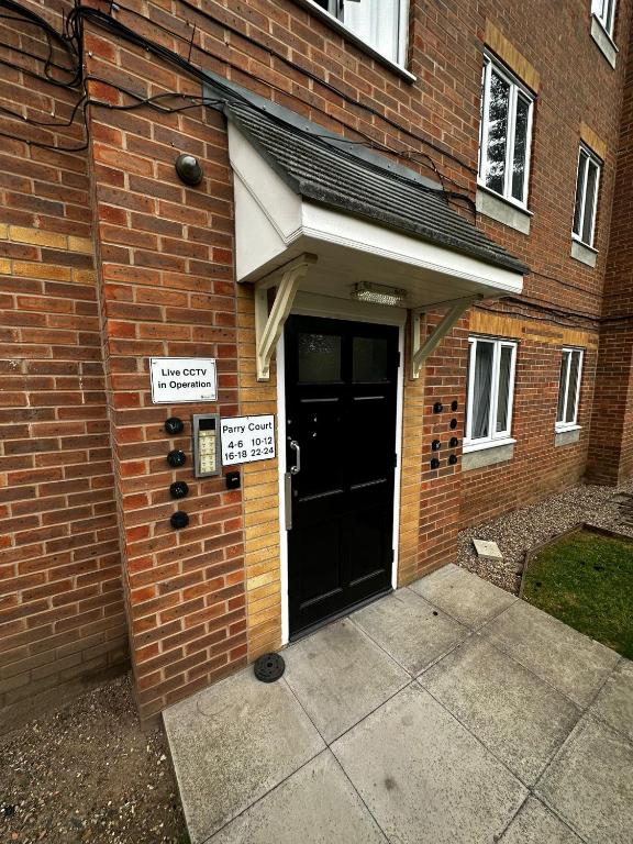 a brick building with a black door with signs on it at 2 Bedroom Apartment - 11 Parry Court in Nottingham