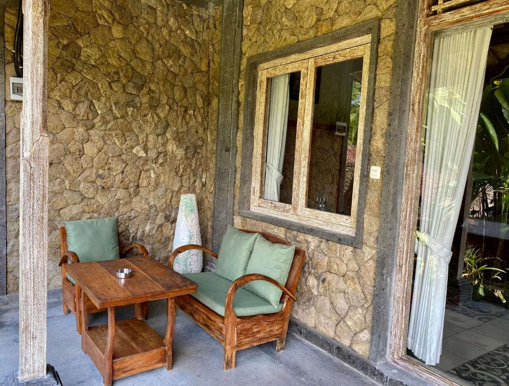 a patio with two chairs and a table and a window at Abian Ayu Villa in Sidemen