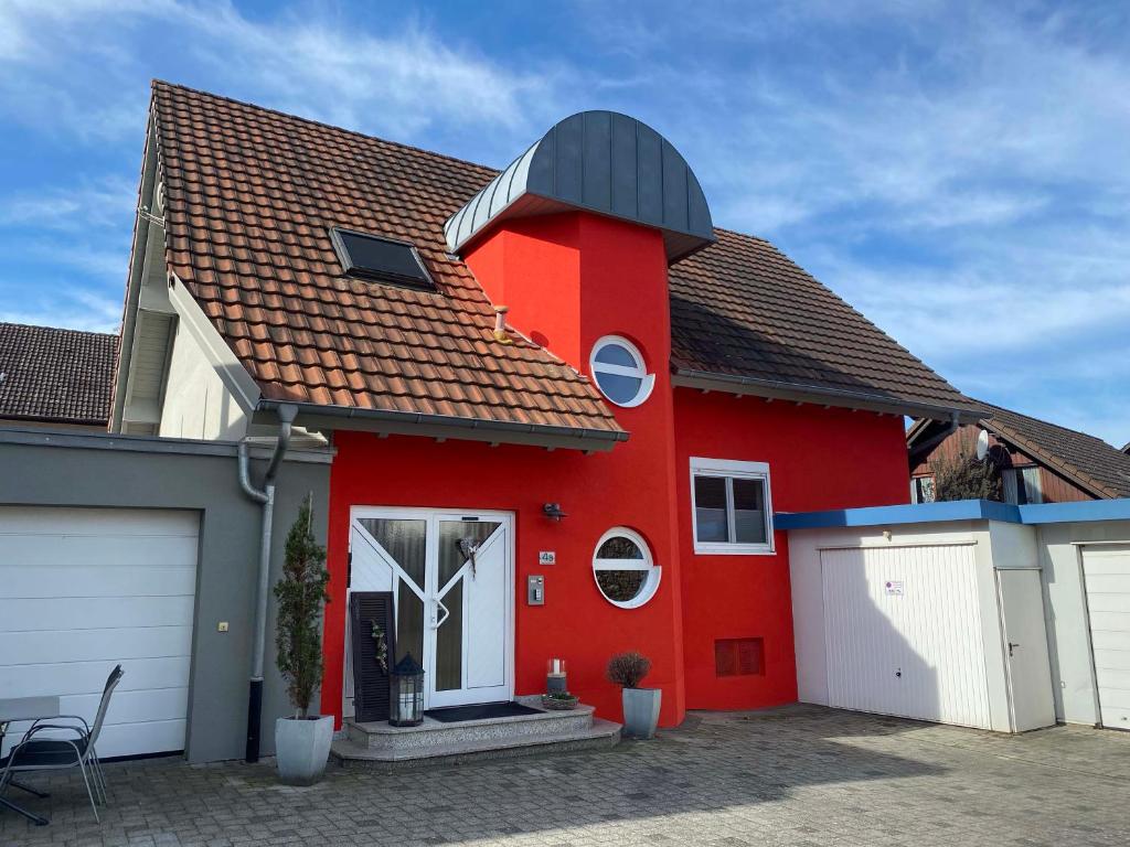 ein rotes Haus mit schwarzem Dach und weißer Garage in der Unterkunft Ferienwohnung Alte B3 in Ringsheim