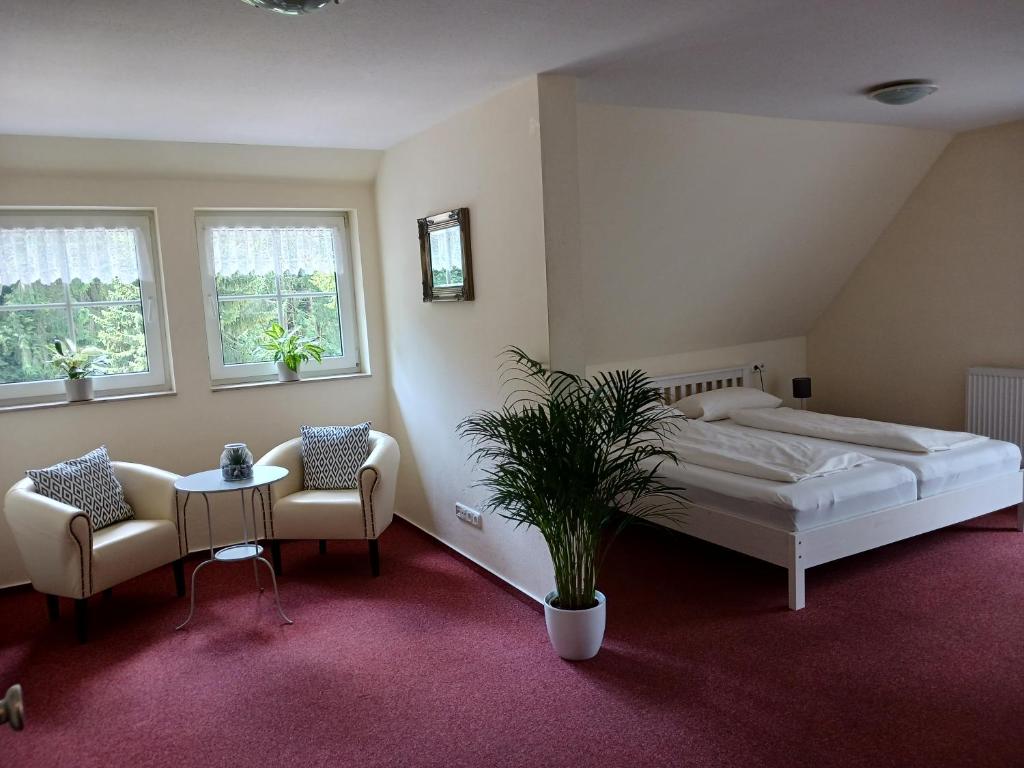 a bedroom with a bed and two chairs and a potted plant at Hotel Forsthaus Glüsing in Schnakenbek