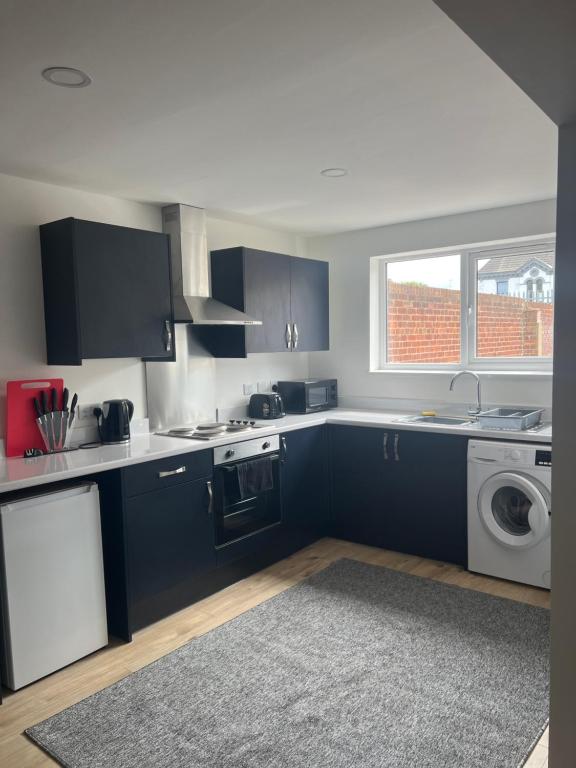 a kitchen with blue cabinets and a washing machine at City apartments college street in Hull