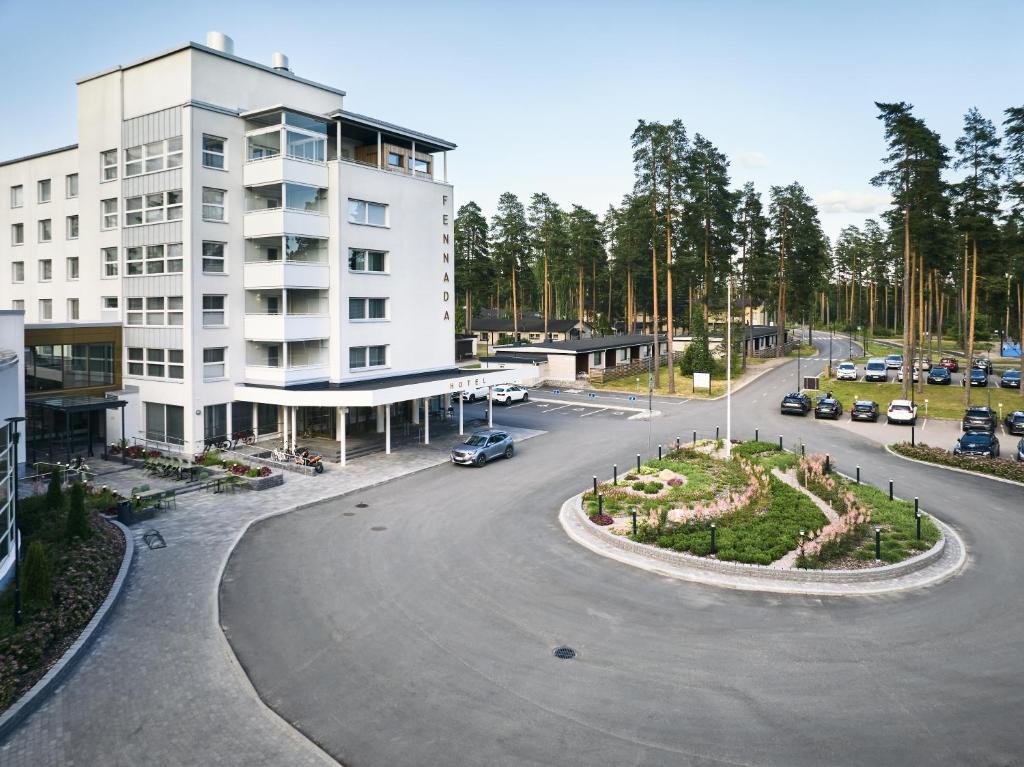 an empty parking lot in front of a white building at Hotelli Fennada in Vierumäki