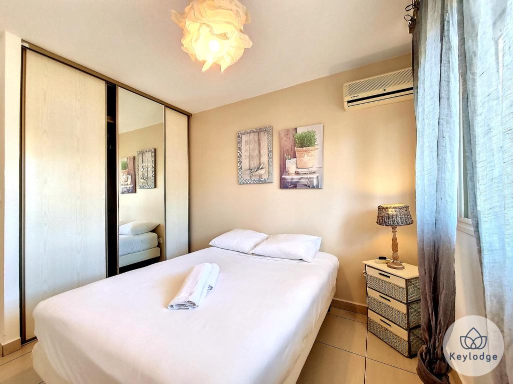 Dormitorio pequeño con cama y espejo en Perle des Camélias-T2 classé 3 étoiles sur Saint-Denis, en Saint-Denis