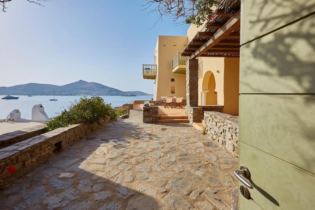 a building with a stone walkway next to the water at Ochre Dream, Beach front & Sunset villa Naousa in Naousa