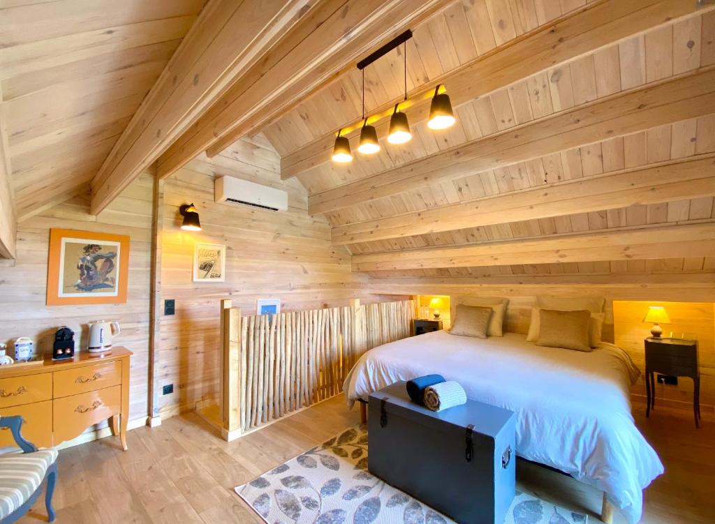a log cabin bedroom with a large bed at La Maison de Manolie in Courcelles-Sapicourt