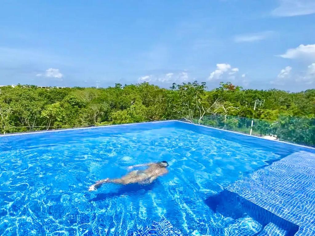 un hombre nadando en una piscina en el agua en BEAUTIFUL SUIT WITH INFINITY POOL AND GYM IN THE MIDDLE OF THE JUNGLe and grill, en Tulum