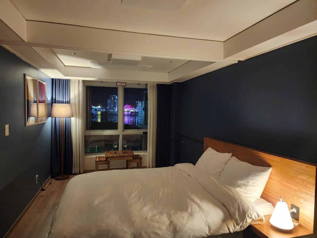 a bedroom with a white bed and a window at Sokcho Marinabay 305 "Lake View" in Sokcho