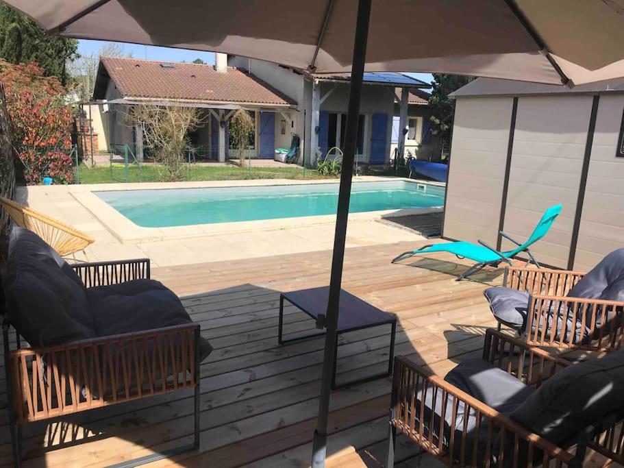 a patio with chairs and an umbrella next to a pool at Maison familiale au cœur du bassin d'Arcachon in Biganos
