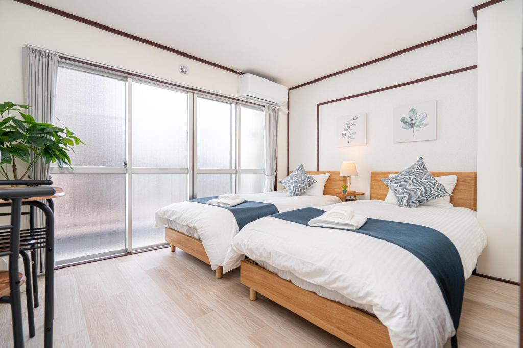 two beds in a room with a large window at NEW OPEN! Nearest JR Shinokubo and JR soubu line HIgashinakano, shinjuku 5 minute ginza 25 minute asakusa 35 minute in Tokyo