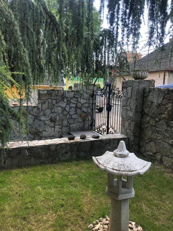 een stenen vogelbad in een tuin met een stenen muur bij Villa Marta in Štúrovo