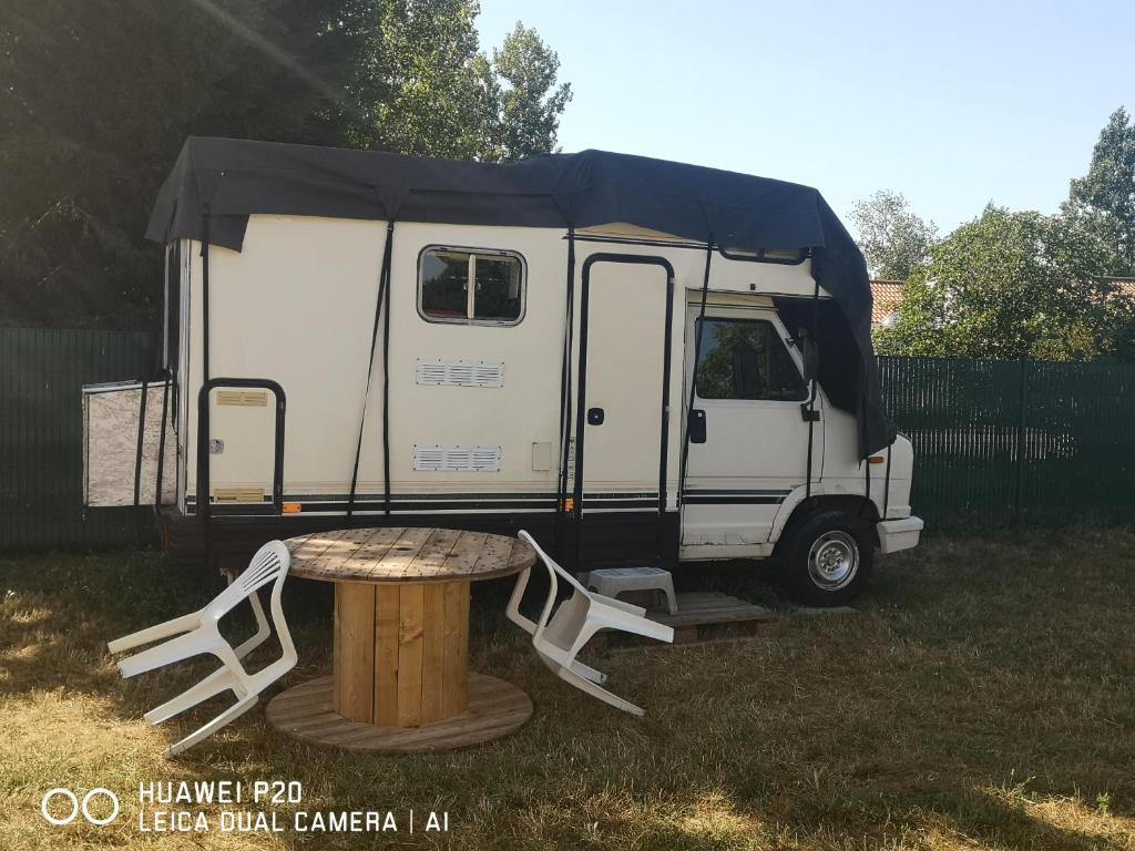 un camping-car avec une table et une tente dans l'établissement chambre en camping car, à Saint-Jean-de-Monts