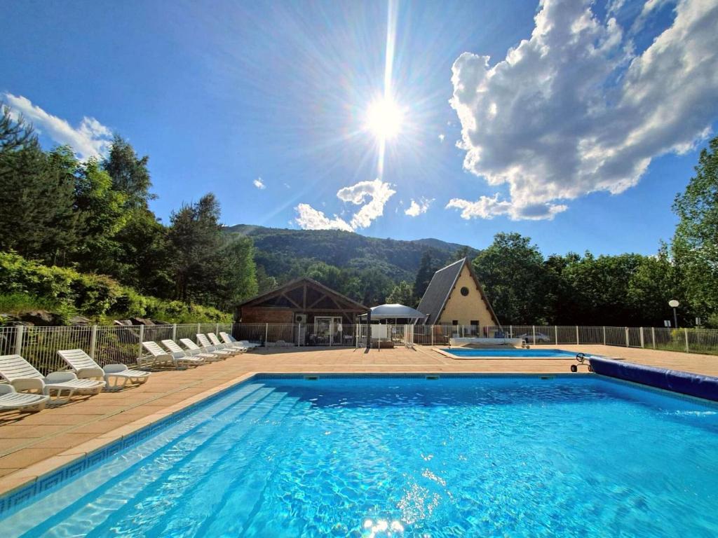 une piscine avec des chaises et une maison dans l'établissement Village de chalets et camping La Pierre de l'Aigle, à La Bréole