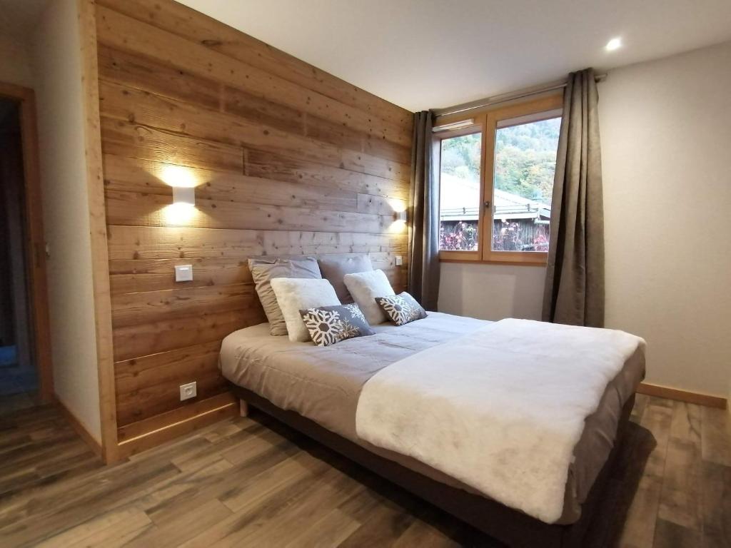 a bedroom with a large bed with a wooden wall at Chez Léon in Samoëns
